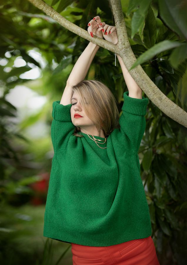 Lifestyle shot in a green knit among tropical leaves
